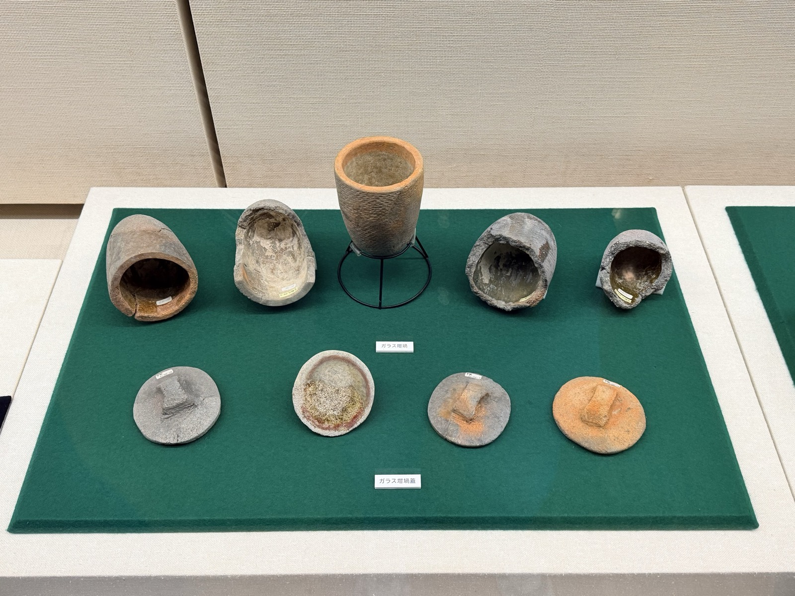 砲弾のような形の土の坩堝が5つと、取っ手のついた丸い蓋が4つ並んでいる
