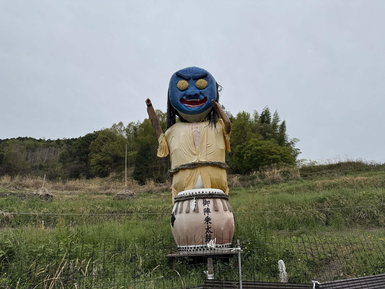 御陣乗太鼓の姿をしたジャンボ案山子。青い鬼の面をかぶり、海藻のような髪を垂らして太鼓の前に立つ