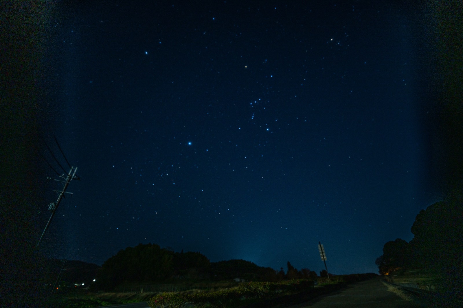 明日香村の冬の夜空。オリオン座がのぼり、手前に電柱と農道のシルエット