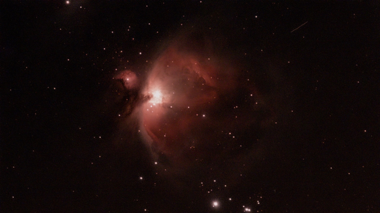 オリオン大星雲。中心の明るい部分から、赤みを帯びたガスが翼のように広がる
