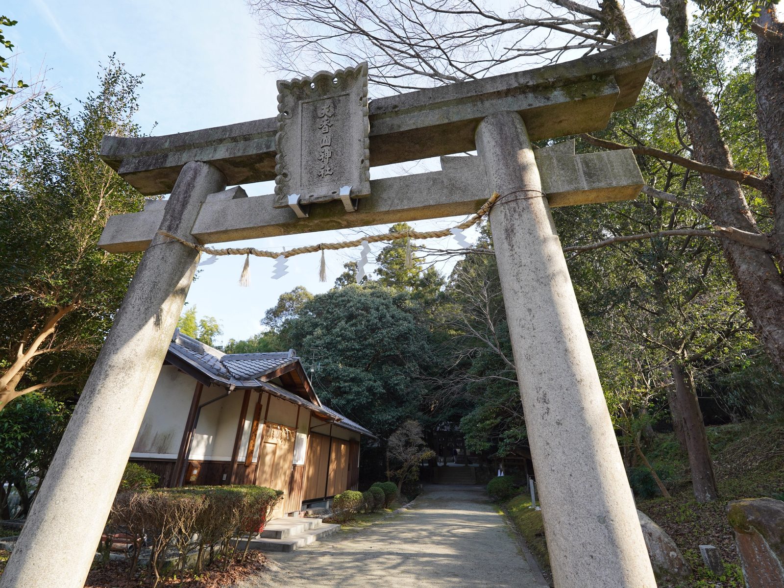 「天香山神社」の扁額を掲げた石の鳥居。参道の先に木立と石段が続く