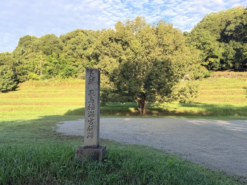 「史跡 飛鳥稲淵宮殿跡」と刻まれた石碑。うしろに広場と木立が広がる