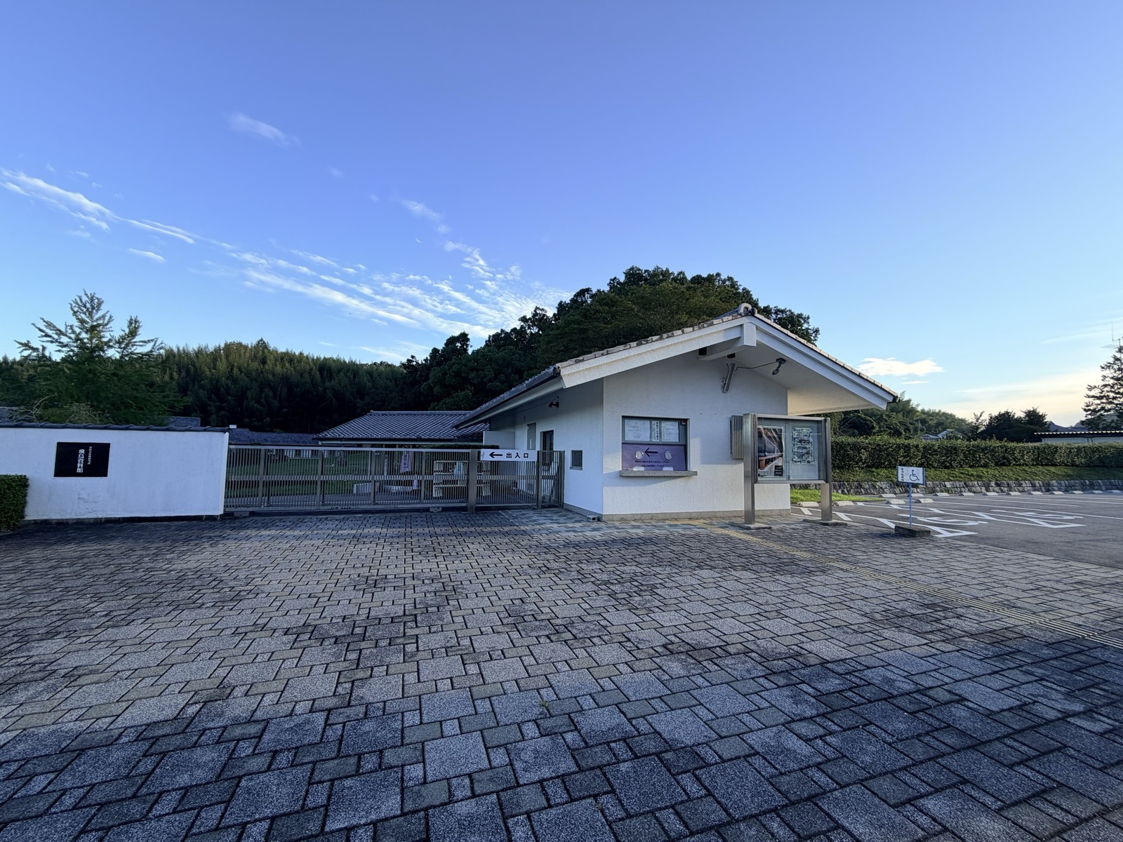 朝の駐車場から見た飛鳥資料館の入口。白壁に館銘板、右手に受付棟、奥は竹林
