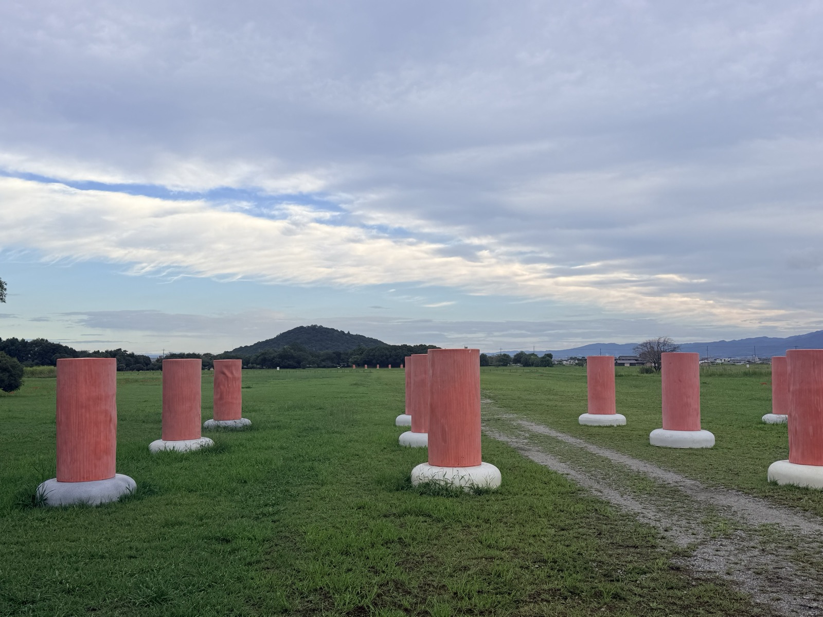 A row of restored vermilion pillars at the Fujiwara Palace Site, with Mt Miminashi, one of the three mountains of Yamato, behind