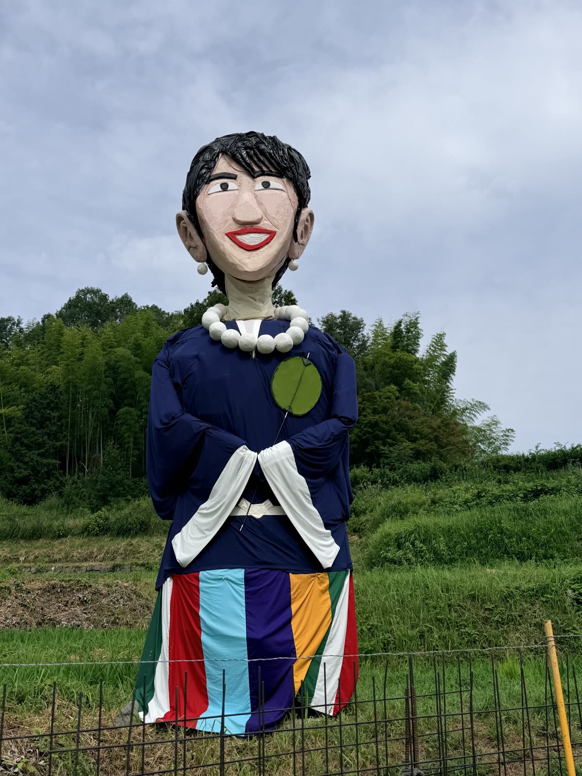 僧侶の姿をしたジャンボ案山子。数珠を手にして棚田に立つ