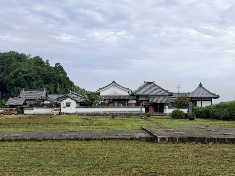 川原寺跡の礎石が並ぶ広場と、その奥に建つ弘福寺の伽藍