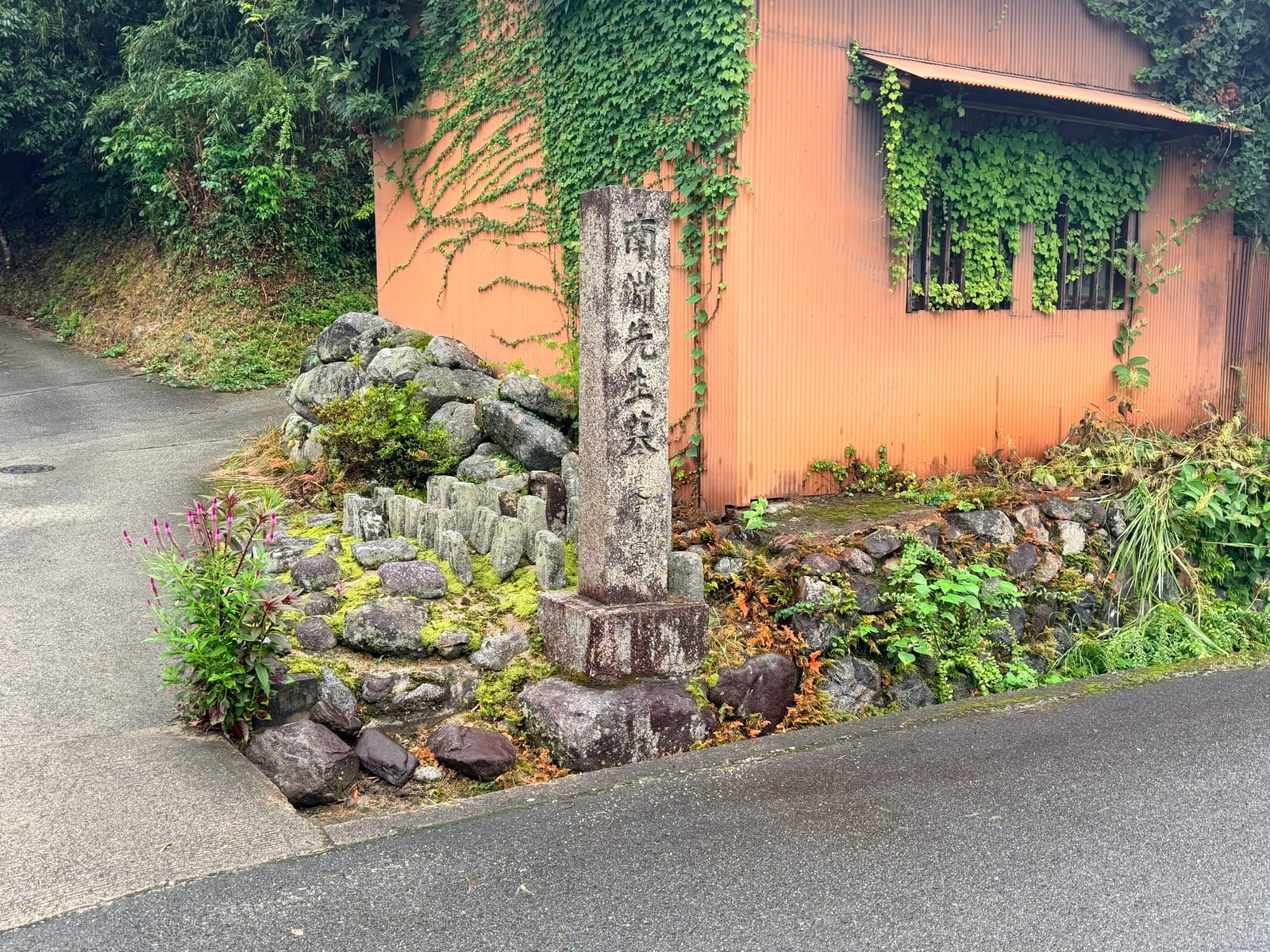 「南淵先生墓」と刻まれた石碑。集落の道の角に、石を積んだ小さな塚とともに立つ