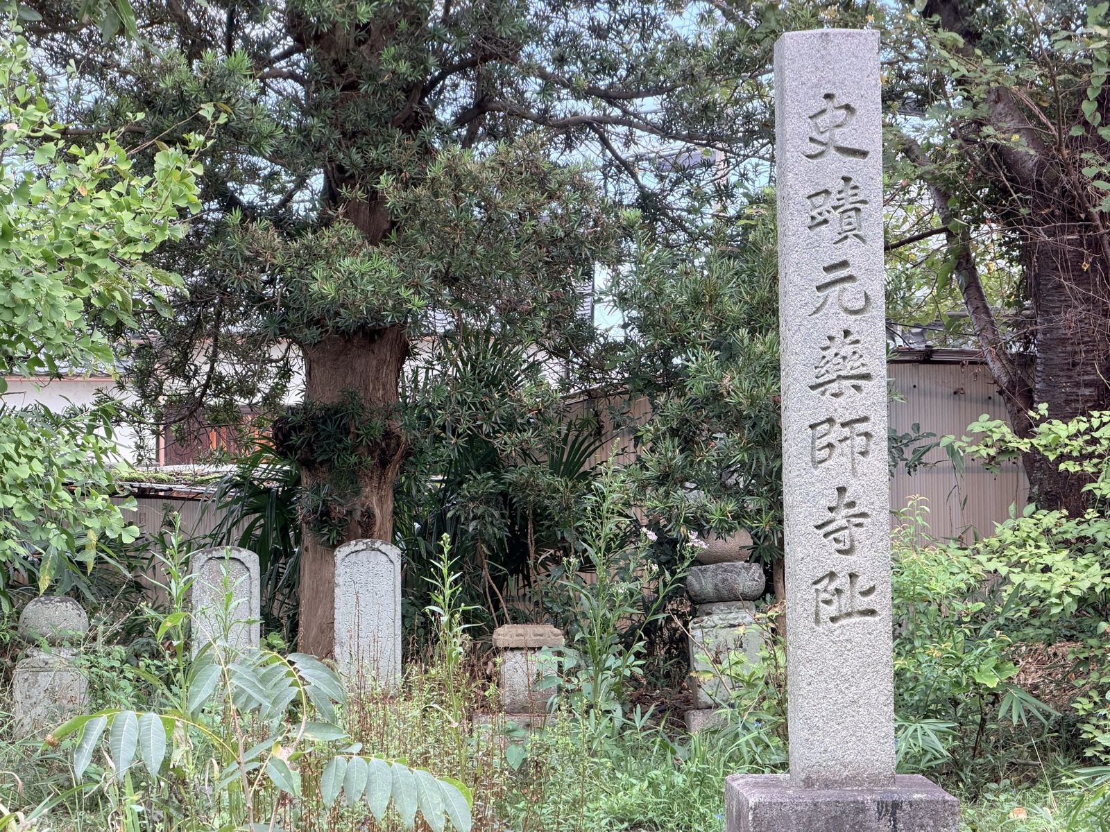 「史蹟 元薬師寺阯」と刻まれた石柱。手前に石仏が並ぶ