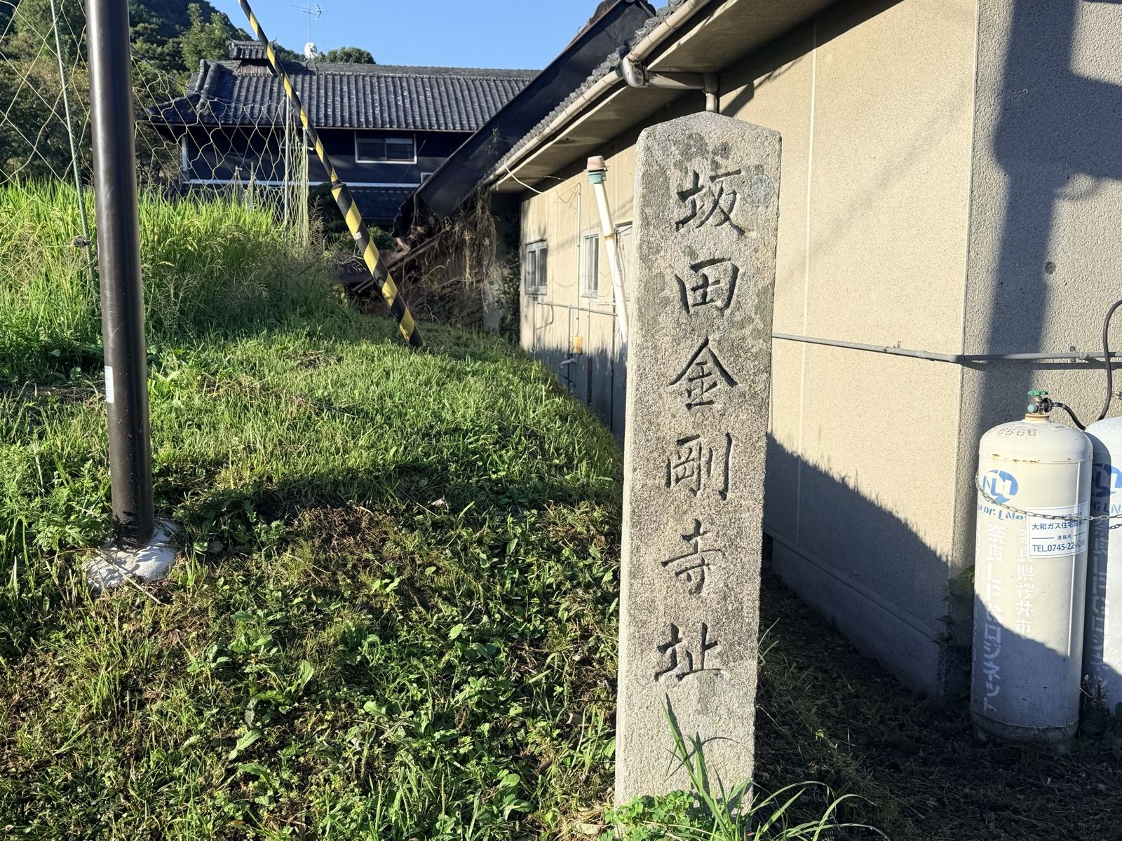 A stone marker inscribed "Site of Sakata Kongō-ji," standing beside a house