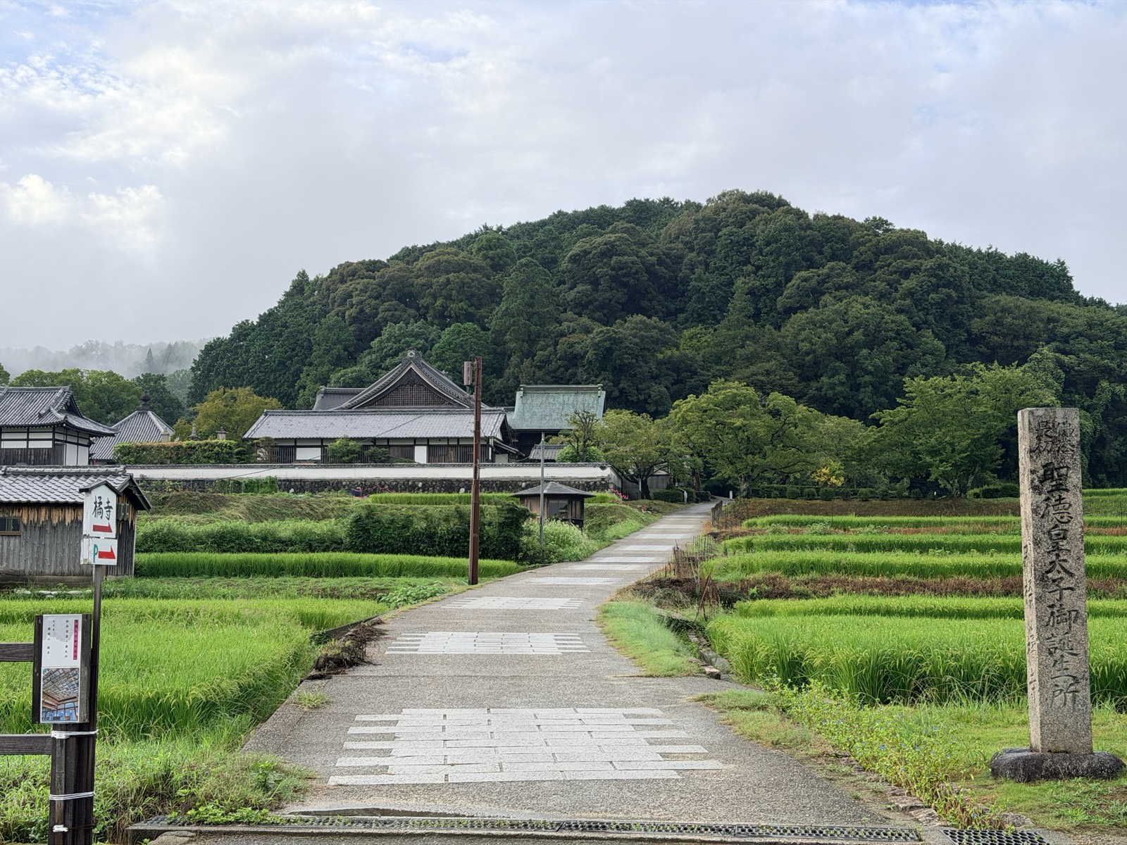田んぼの中をまっすぐ延びる橘寺への参道と、「聖徳皇太子御誕生所」の石標