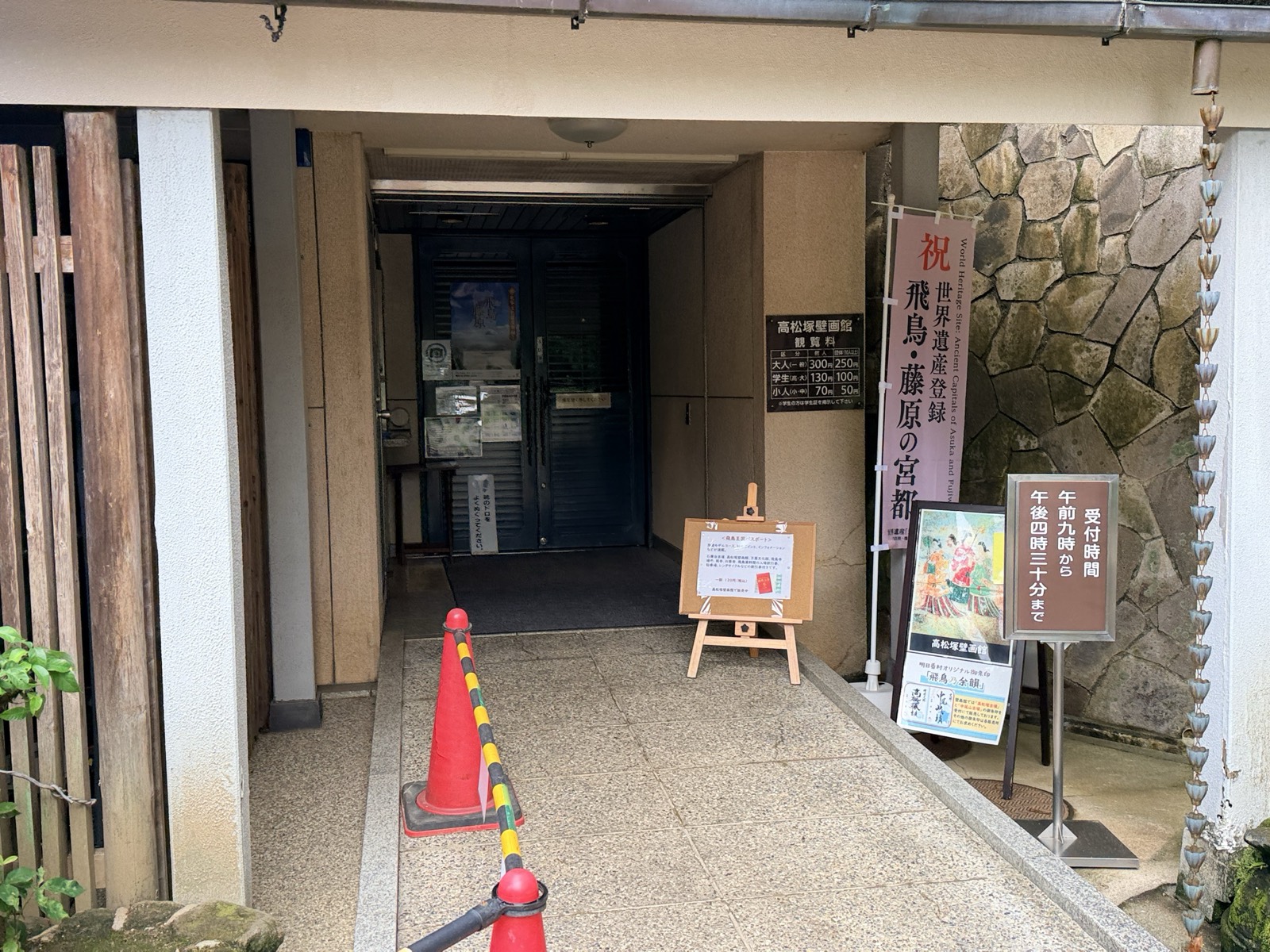 高松塚壁画館の入口。観覧料と受付時間の掲示、世界遺産登録を祝うのぼりが並ぶ