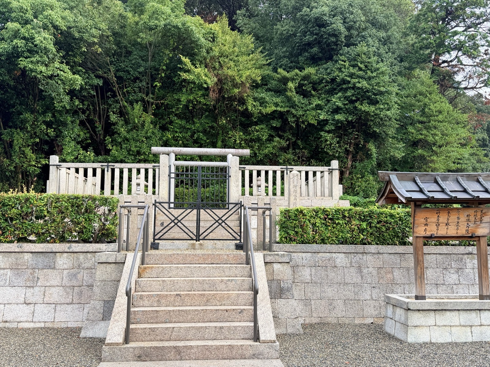 天武・持統天皇陵の拝所。石段の上に黒い門扉と石の玉垣、右手に宮内庁の制札が立つ